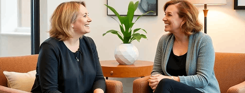 two women talking compassionately in comfortable office setting, warm and welcoming